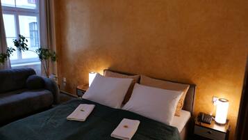 A hotel room with a bed, two bedside tables, a nightstand, a lamp, and a couch.