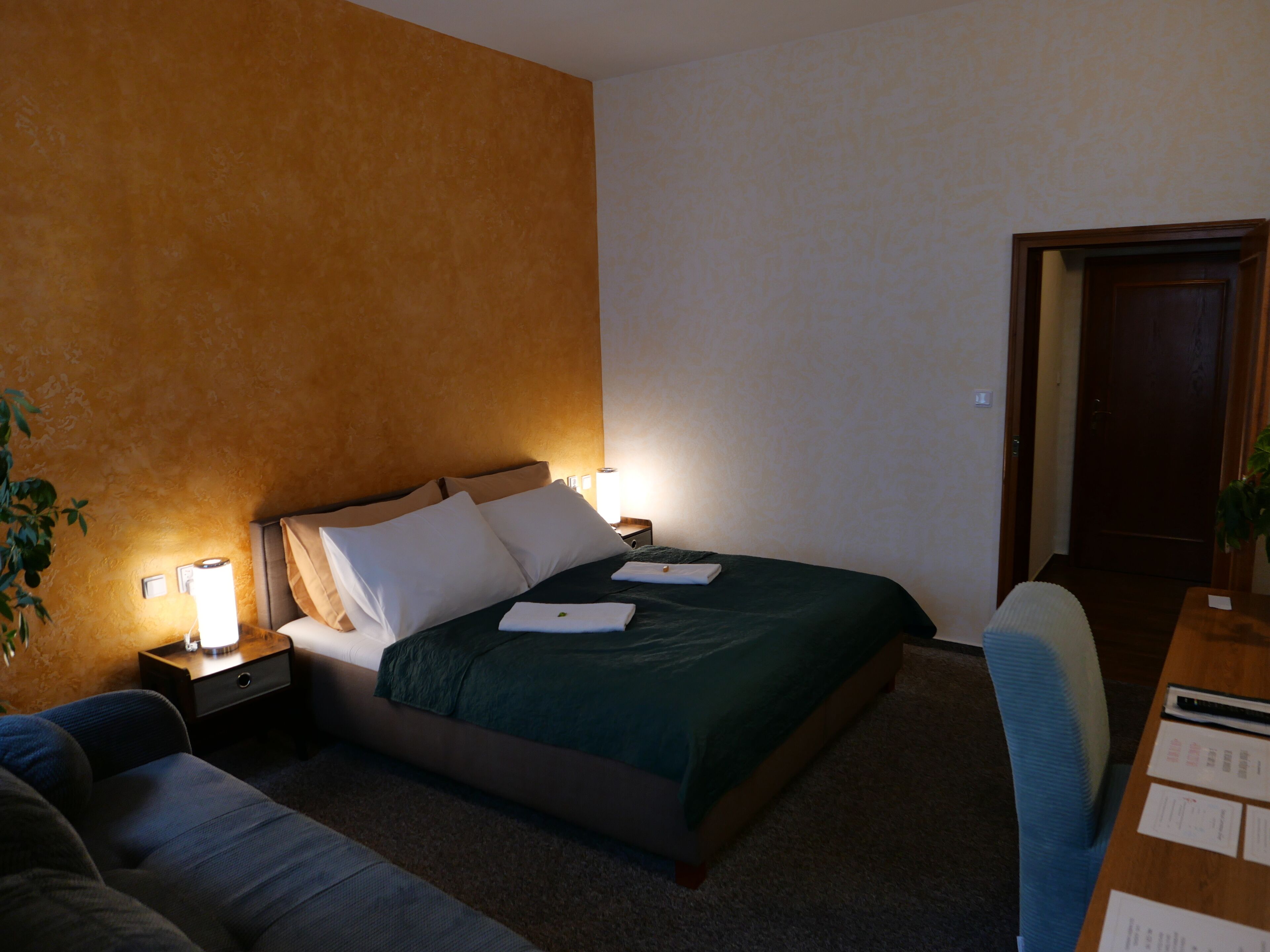 A hotel room with a bed, a nightstand, a desk, and a chair.