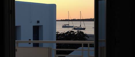 A balcony with a view of boats on the water during sunset.