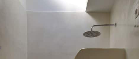 A small, enclosed shower area with a toilet and a sink.