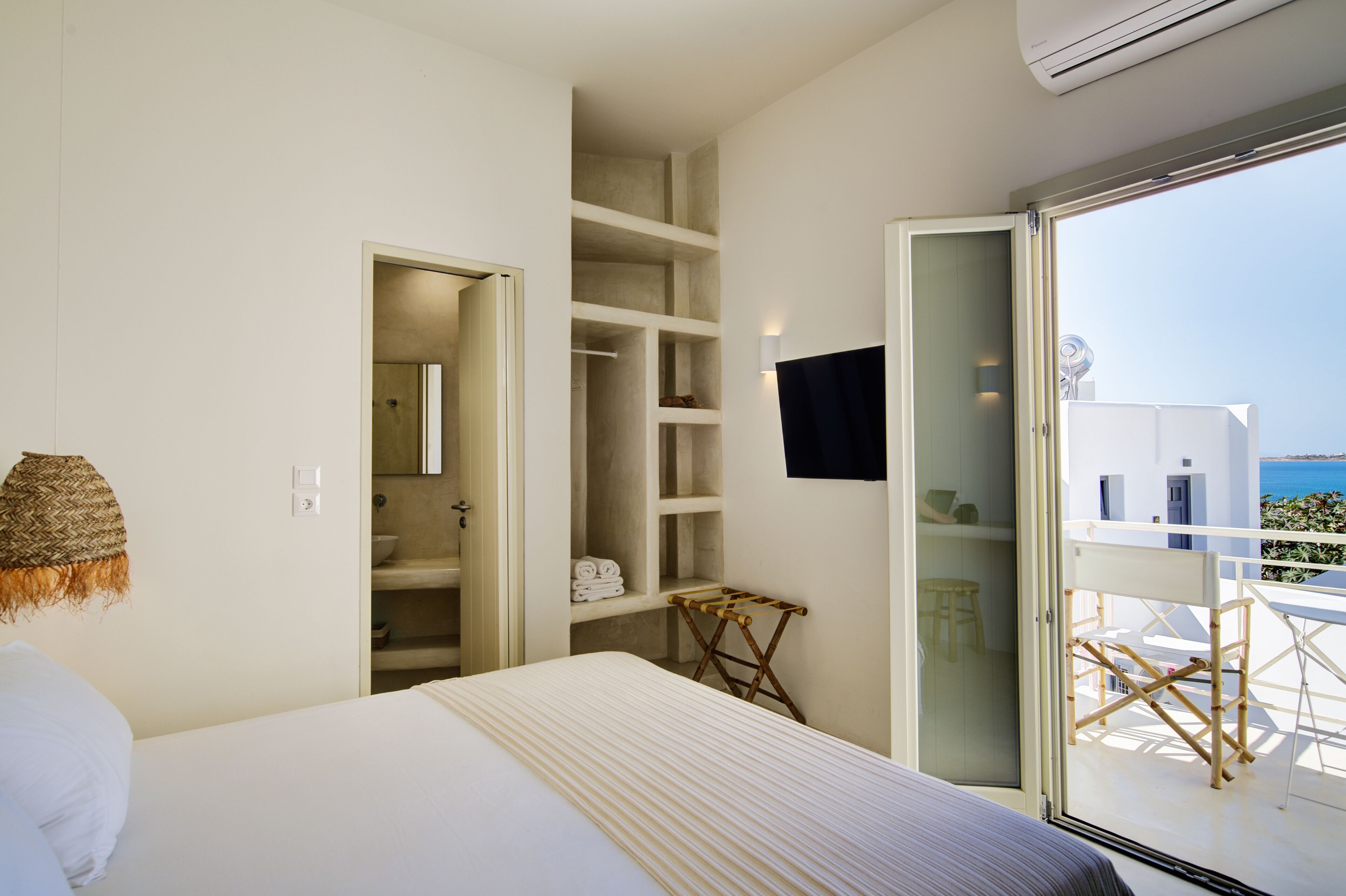 Habitación de hotel con cama, armario, balcón con vistas y televisión.