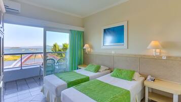 Habitación de hotel con dos camas, un balcón con vistas al mar y un cuadro en la pared.
