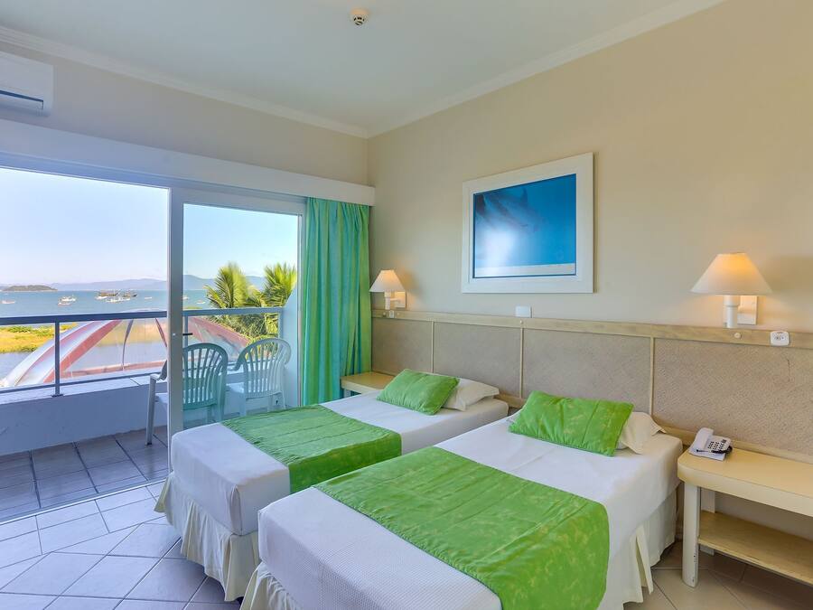 Habitación de hotel con dos camas, un balcón con vistas al mar y un cuadro en la pared.