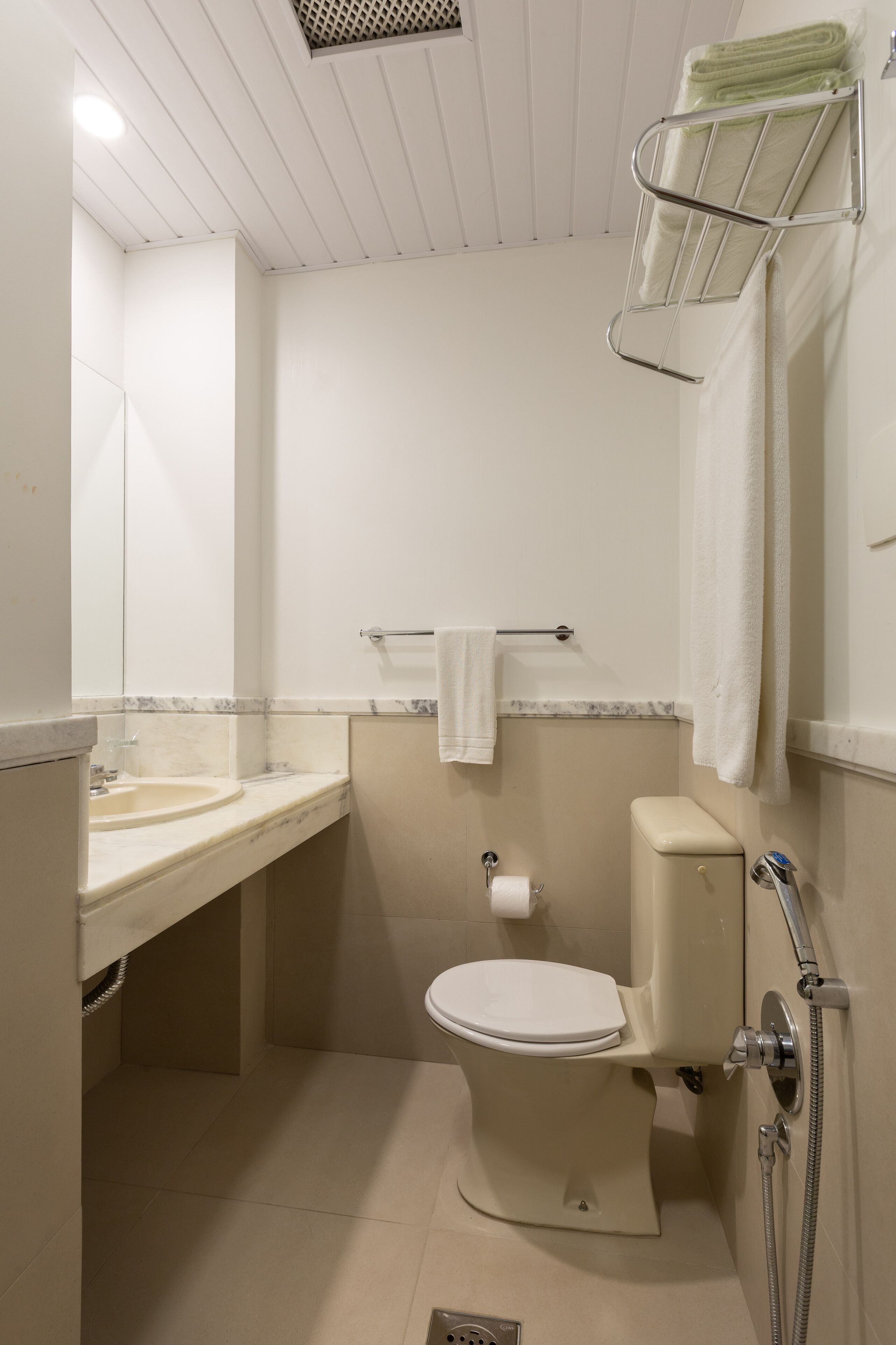 Un baño pequeño y funcional con inodoro, lavabo y perchero para toallas.