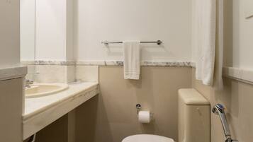 A compact bathroom with a toilet, sink, and towel rack.