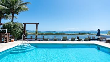 Una piscina techada, una piscina al aire libre, sombrillas