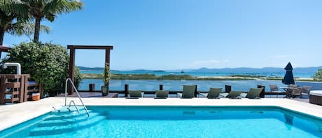 Una piscina techada, una piscina al aire libre, sombrillas