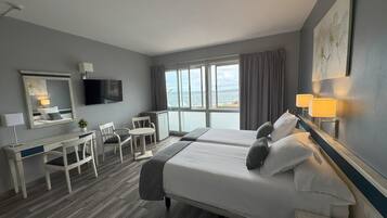 A hotel room with a bed, desk, chair, and a TV.