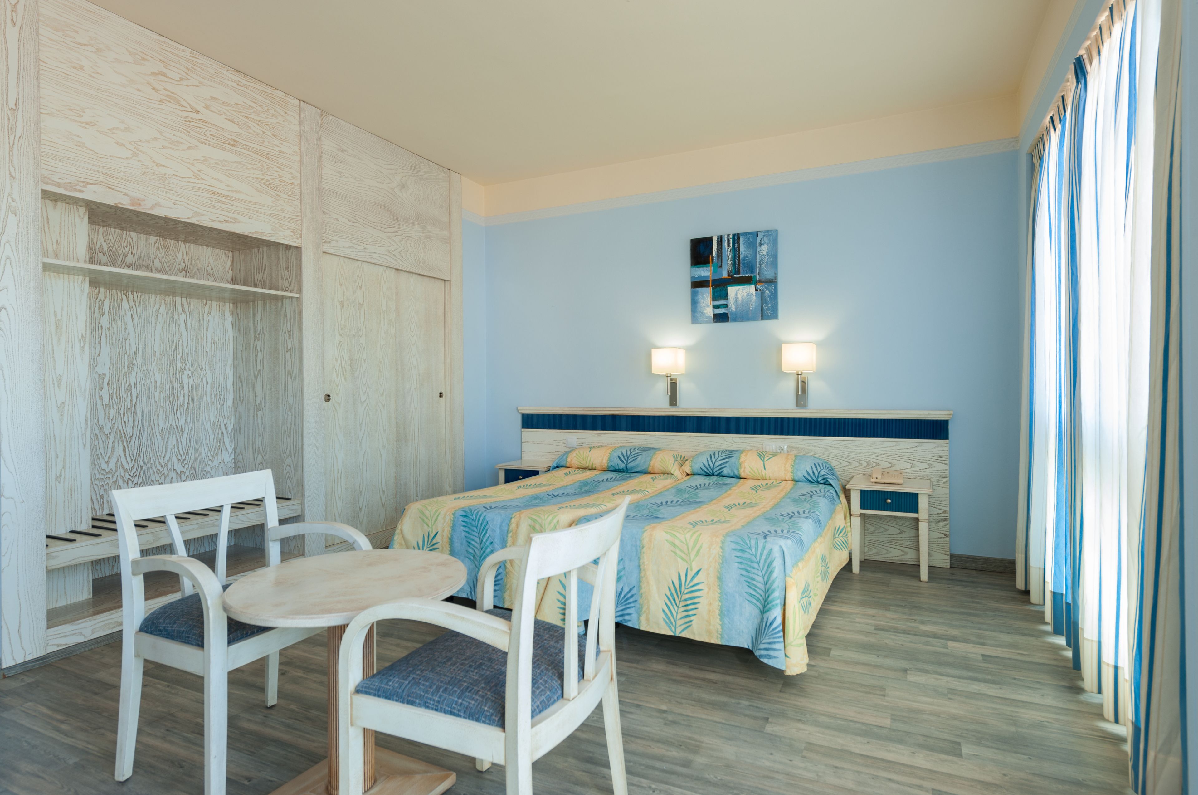 Ein Hotelzimmer mit einem Bett, zwei Nachttischen, einem Schreibtisch mit Stuhl und einem Kleiderschrank.