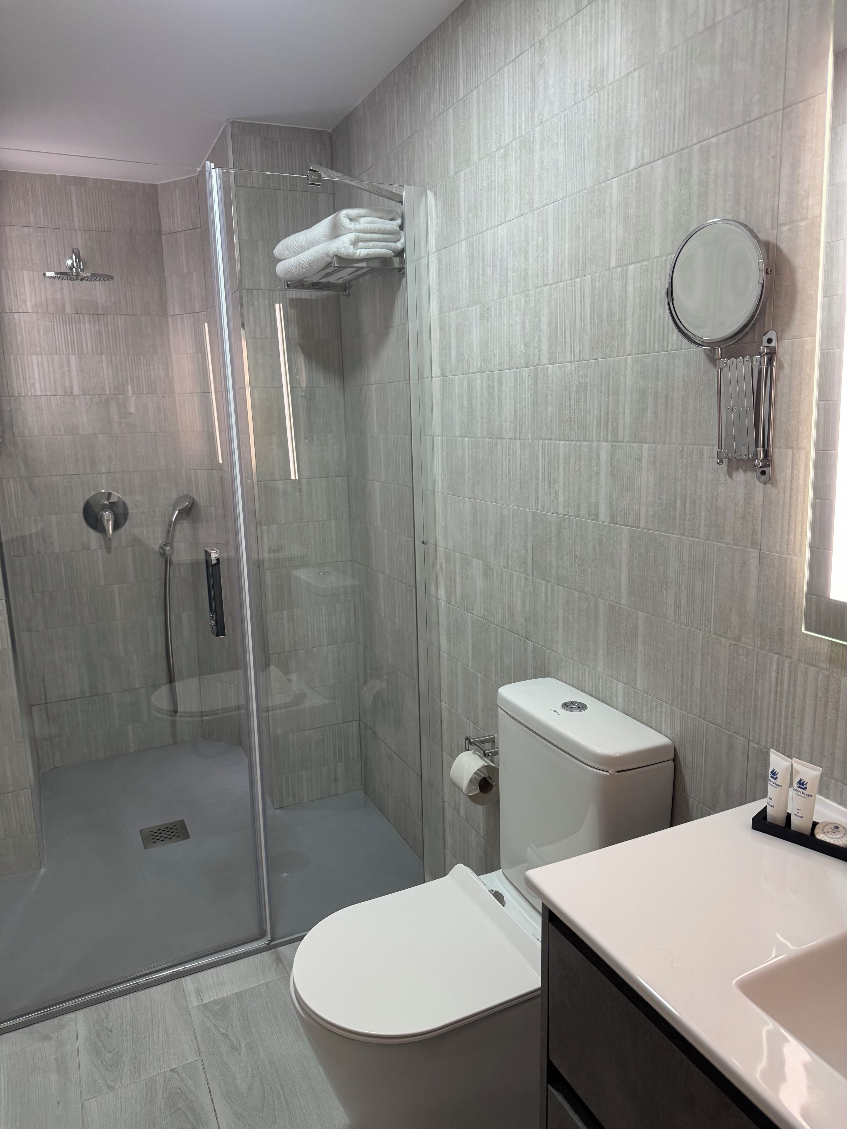 A modern bathroom with a glass-enclosed shower, a toilet, and a sink.