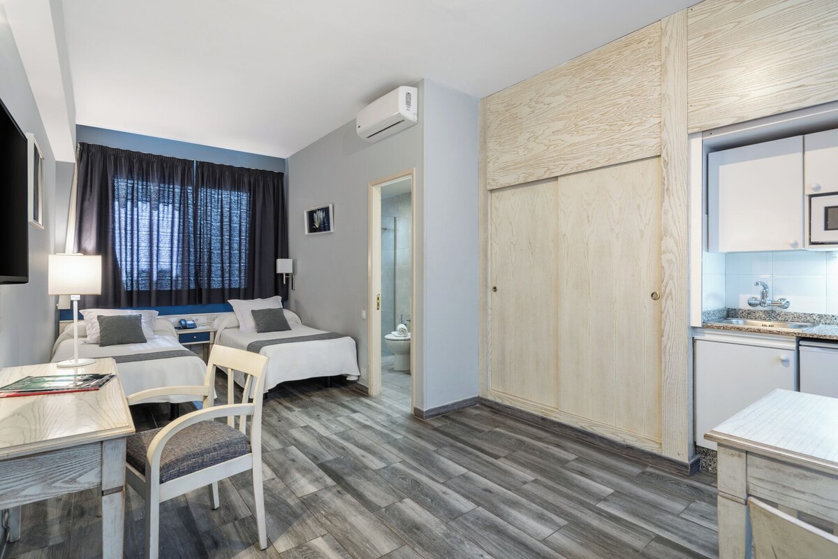 Une chambre d’hôtel équipée d’un lit, d’un bureau, d’une chaise et d’une kitchenette.