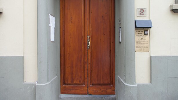 A wooden double door with a brass handle, a small sign above it, and a number '2' on the wall to the right. - Bed & Bed Cassia (Florence)