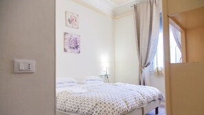 A bedroom with a bed, a bedside table, a lamp, and two wall-mounted pictures. - Bed & Bed Cassia (Florence)
