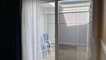 Ein Zimmer mit einer Schiebeglastür, die zu einem Außenbereich mit Terrassenstuhl und weißer Wand führt.