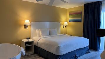 Ein Hotelzimmer mit einem Bett, Nachttischen, einem Deckenventilator und einem Bild an der Wand.