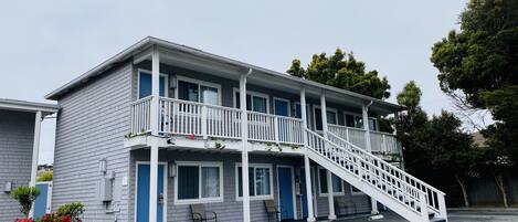 A two-story motel with a central staircase, multiple windows, and a parking lot.