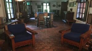 Una stanza con due poltrone in legno dotate di cuscini blu, un tavolo in legno e un pavimento piastrellato ad esagono.