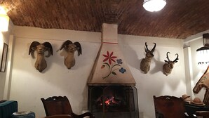 Un interno rustico con camino, mobili in legno e teste di animali appese alle pareti.