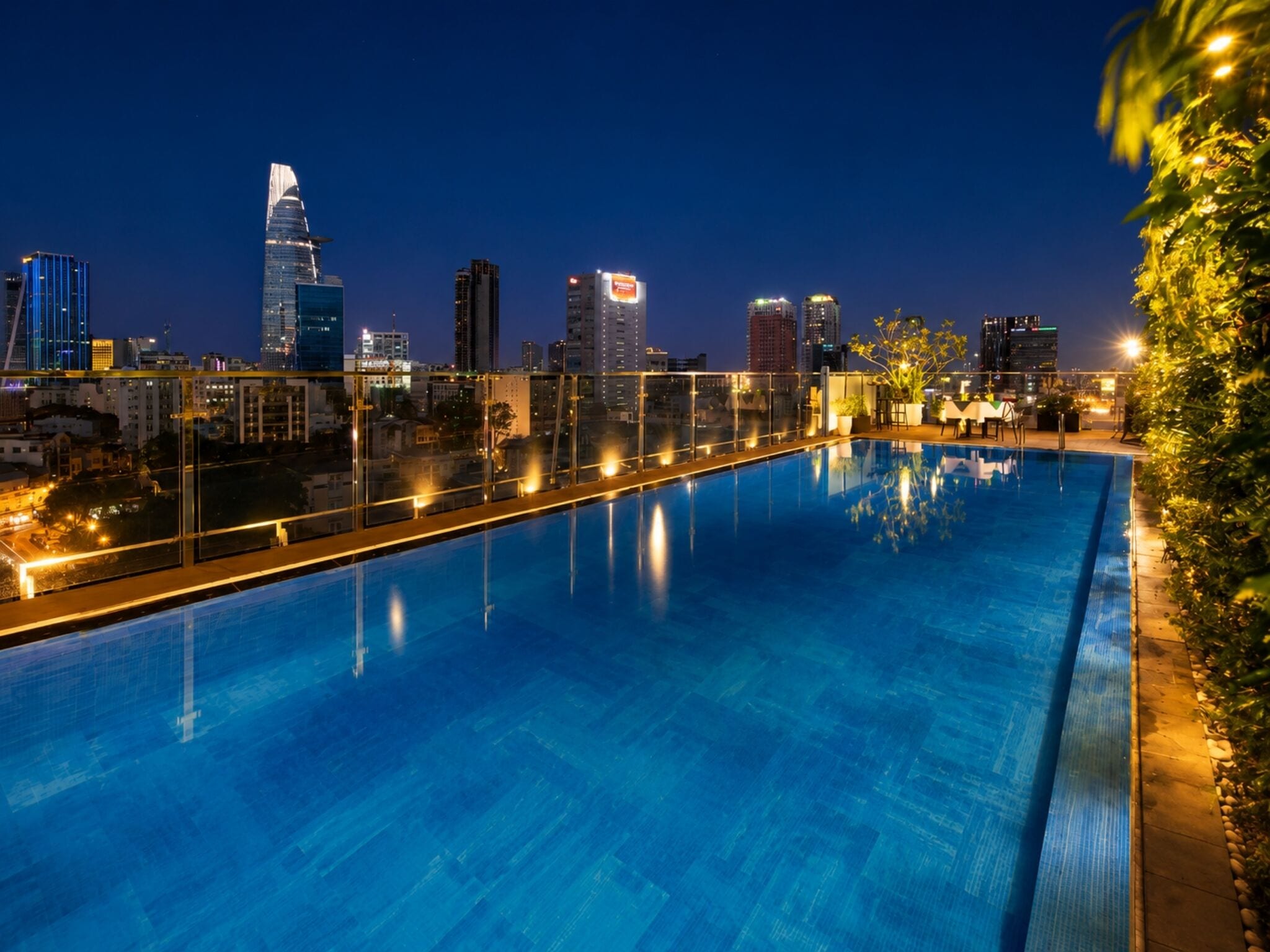Una piscina en la azotea con vistas al horizonte urbano, que incluye edificios altos y un rascacielos distintivo.