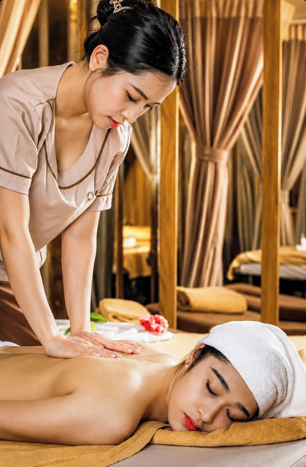 Une personne reçoit un massage dans une pièce dont le mobilier et les rideaux sont en bois.