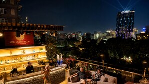 A rooftop bar with a city view, seating arrangements, and a bar counter. - Happy Life Grand Hotel & Sky Bar (Ho Chi Minh City)