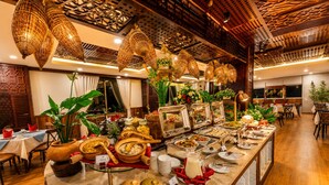 A buffet setup with various food items and a wooden ceiling with hanging lights. - Happy Life Grand Hotel & Sky Bar (Ho Chi Minh City)