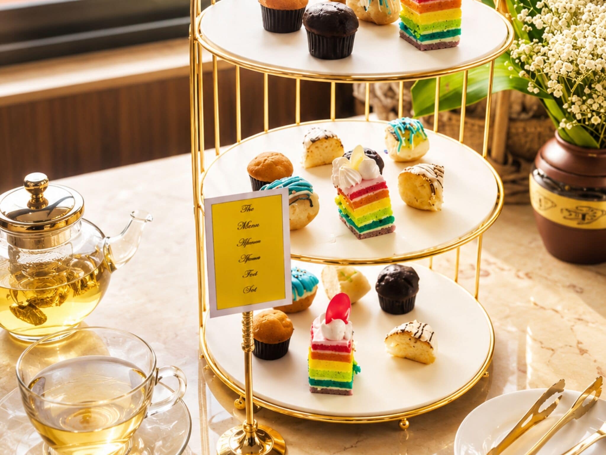 A tiered dessert stand with various pastries and a menu sign.