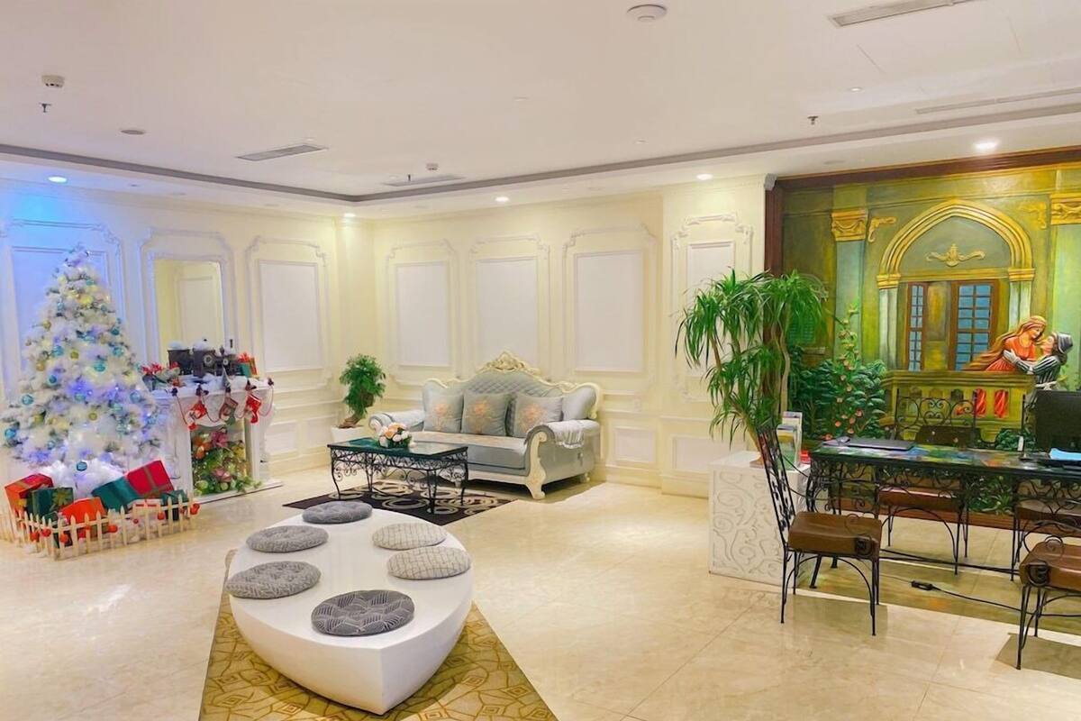 A spacious living area with a white sofa, a coffee table, a Christmas tree, and a large window with a view.