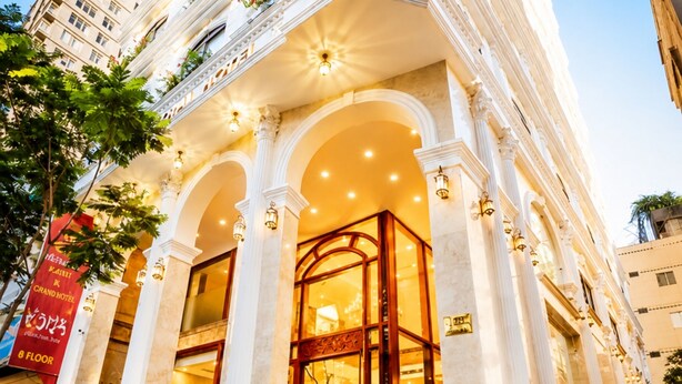 A grand hotel entrance with classical architecture, including columns and arches, and a staircase leading to the lobby. - Happy Life Grand Hotel & Sky Bar (Ho Chi Minh City)