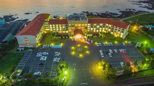 Un hôtel doté d’une cour intérieure, d’un parking et offrant une vue sur la mer au crépuscule.