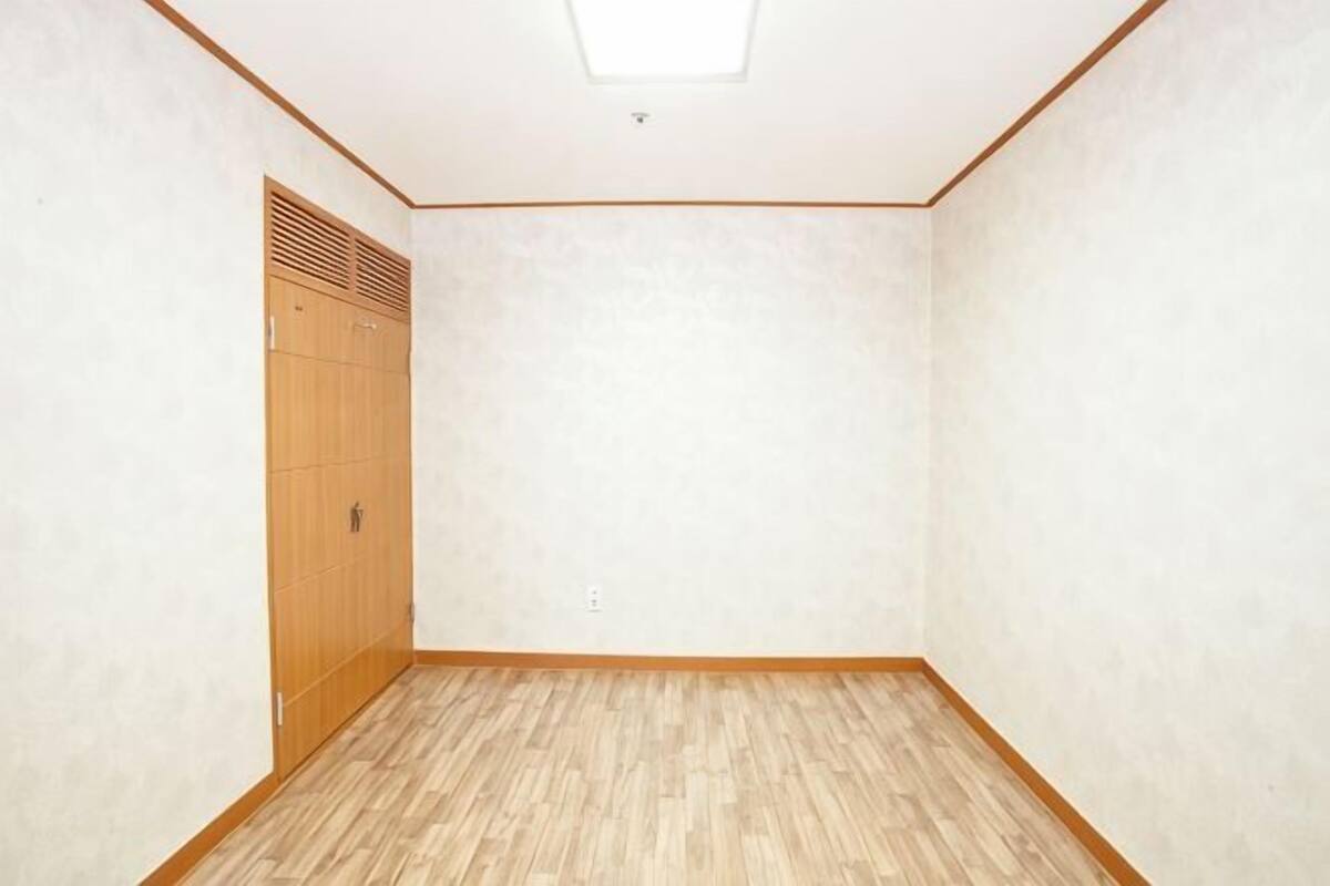 Une pièce avec un plancher en bois, une armoire et un luminaire au plafond.