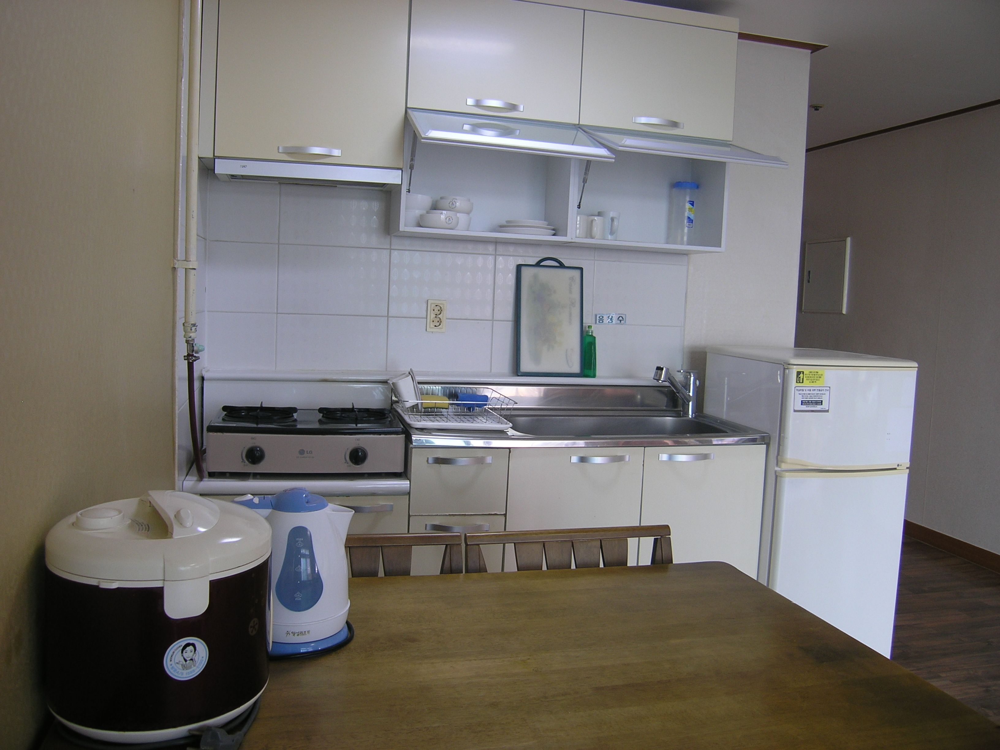 Uma cozinha compacta com armários brancos, fogão, pia e geladeira.