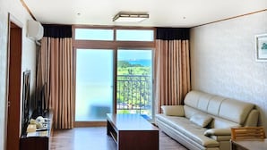 Un salon avec un canapé, une table basse, un téléviseur et un balcon offrant une vue sur la mer.