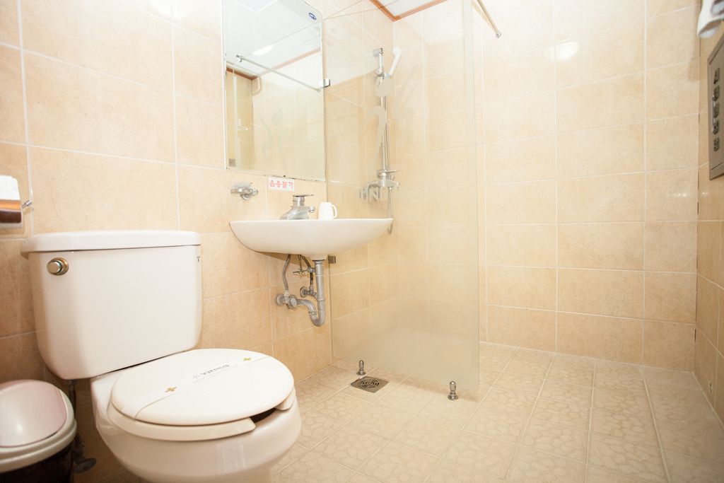 A bathroom with a toilet, sink, and shower.