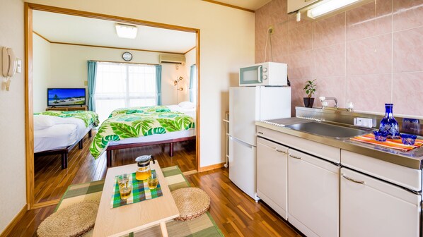 A compact room with a bed, a small table with drinks, a microwave, and a sink. - HOTEL Sunset ZANPA (Yomitan)