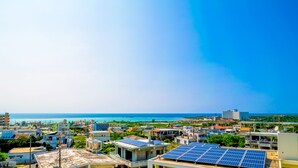 Un paisaje urbano costero con edificios residenciales, paneles solares en los tejados y una vista despejada del océano.