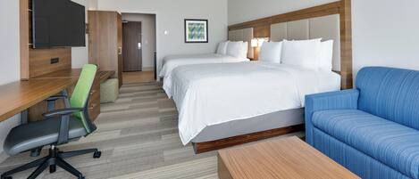 Una habitación de hotel con una cama, un escritorio, una silla, un sofá y una televisión.