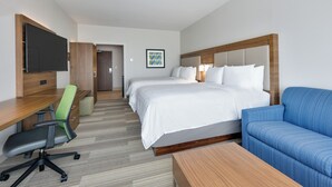 Een hotelkamer met een bed, een bureau met stoel, een televisie en een bank.