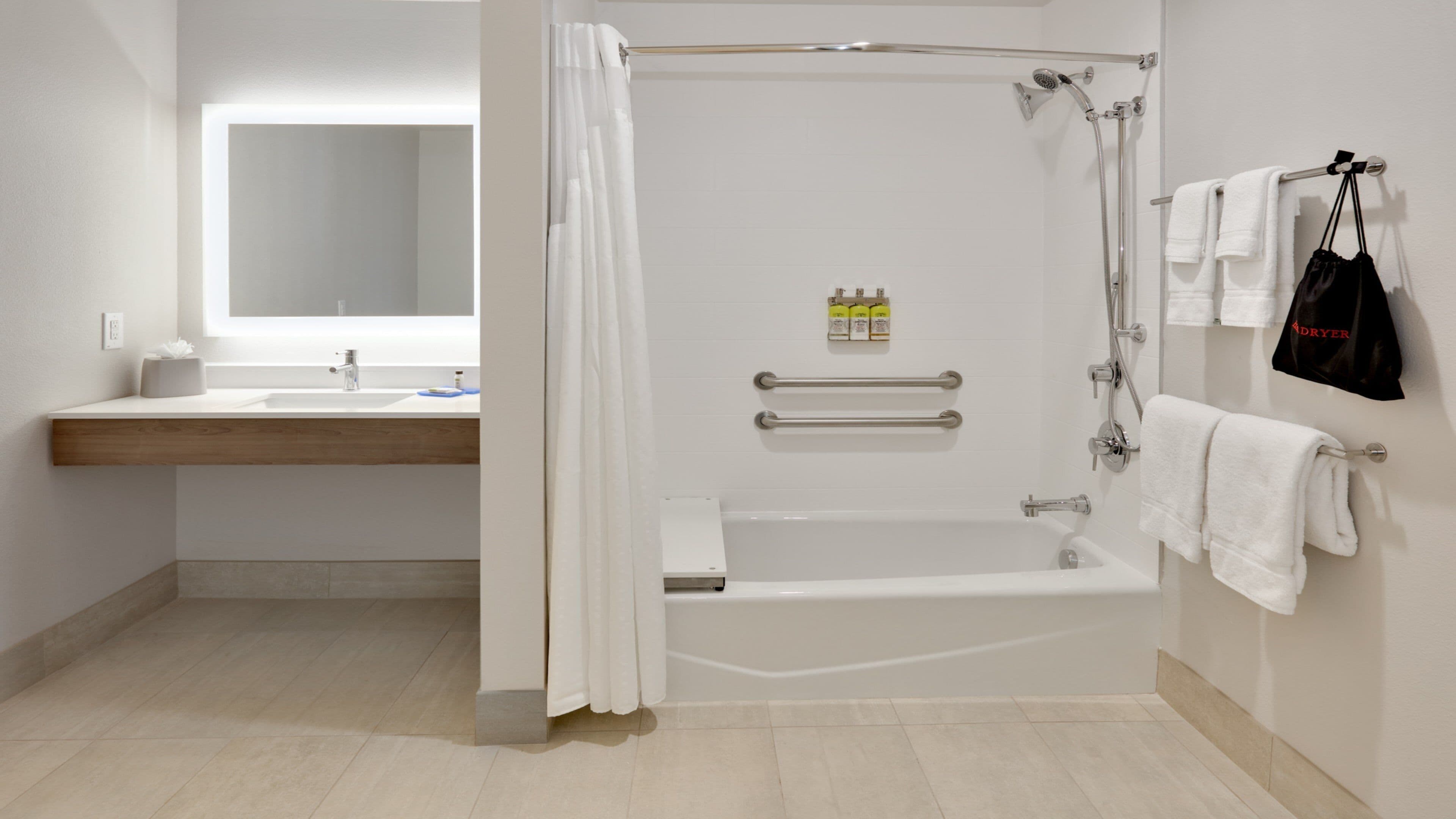 Un baño moderno con ducha, lavamanos y espejo.