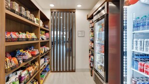 Een schap met diverse snacks en verpakte producten, en een koelgedeelte met drankjes.