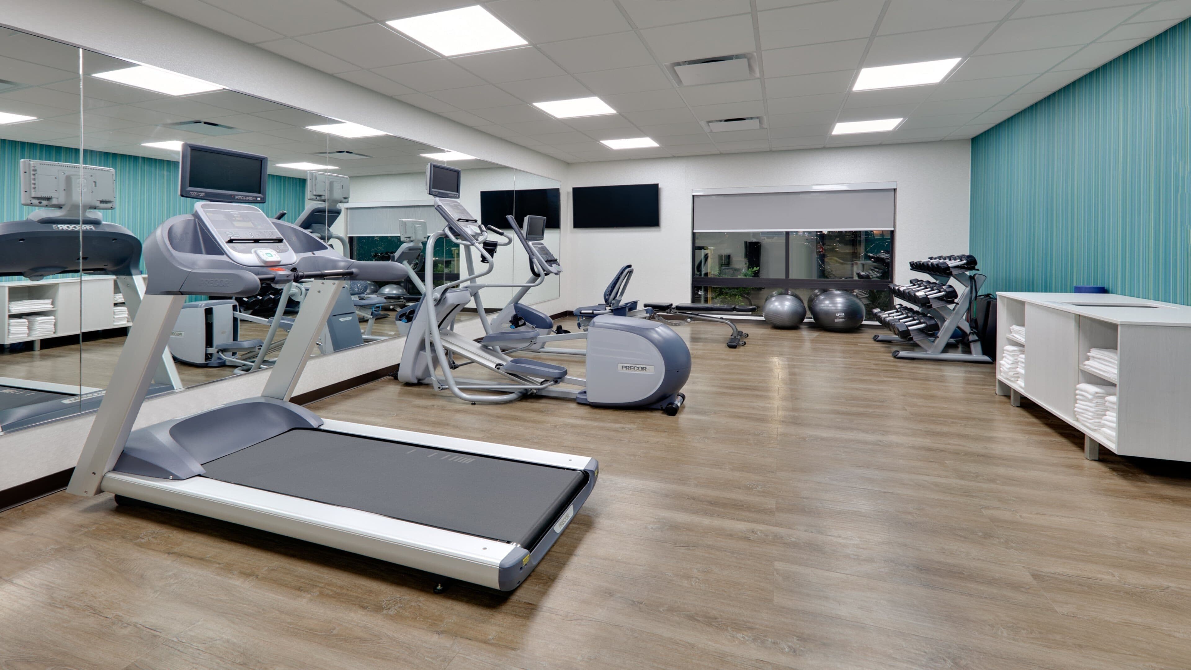 Un gimnasio con cintas de correr, elípticas y pesas libres.