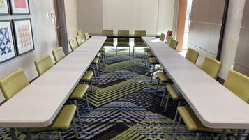 A conference room with a long table, yellow chairs, patterned carpet, and framed artwork on the walls.