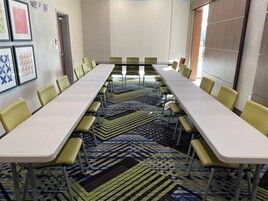 A conference room with a long table, yellow chairs, patterned carpet, and framed artwork on the walls.