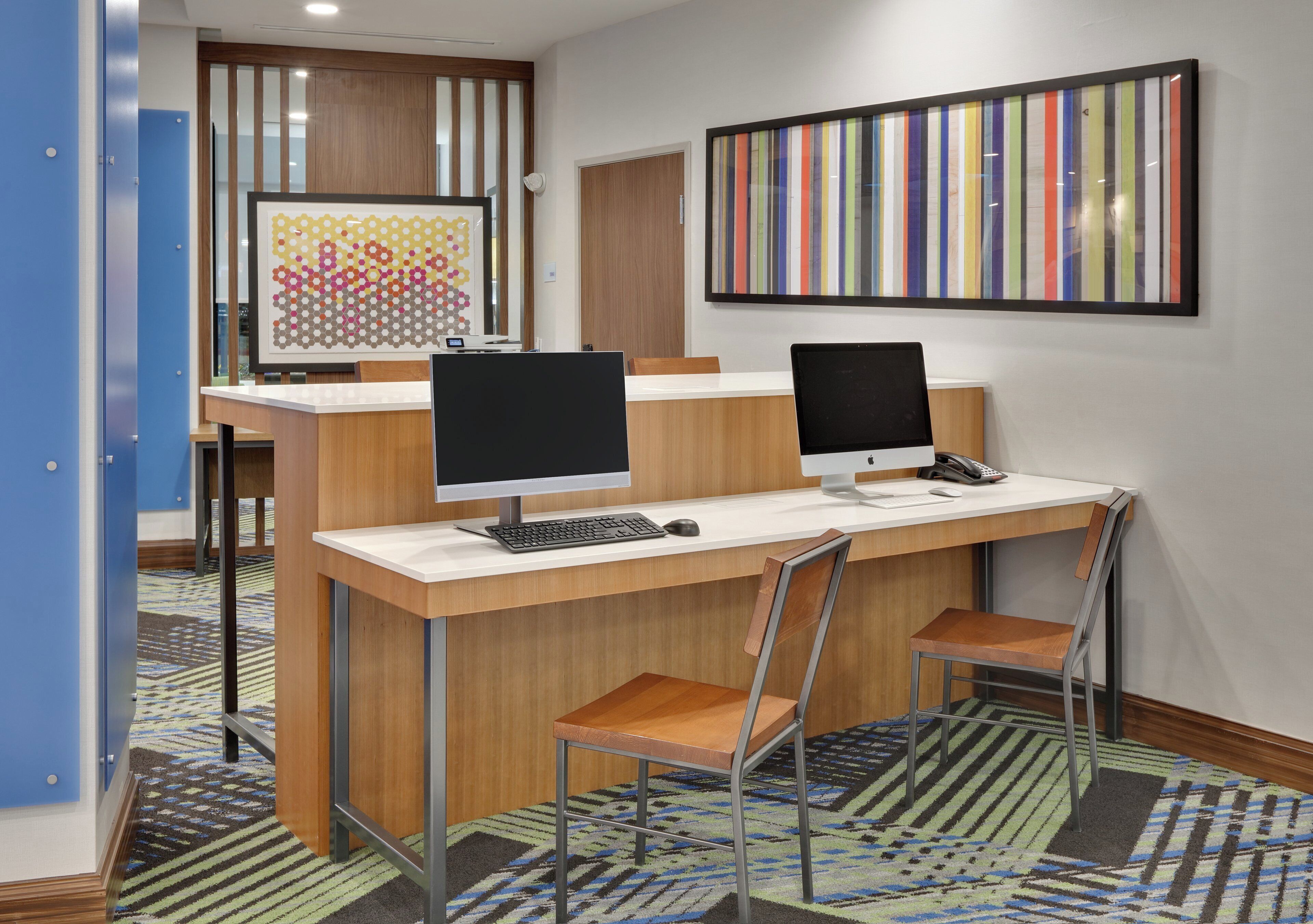 A modern office space with two desks, each with a computer and keyboard, and a chair.