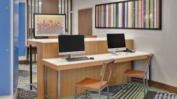 A modern office space with two desks, each with a computer and keyboard, and a chair.