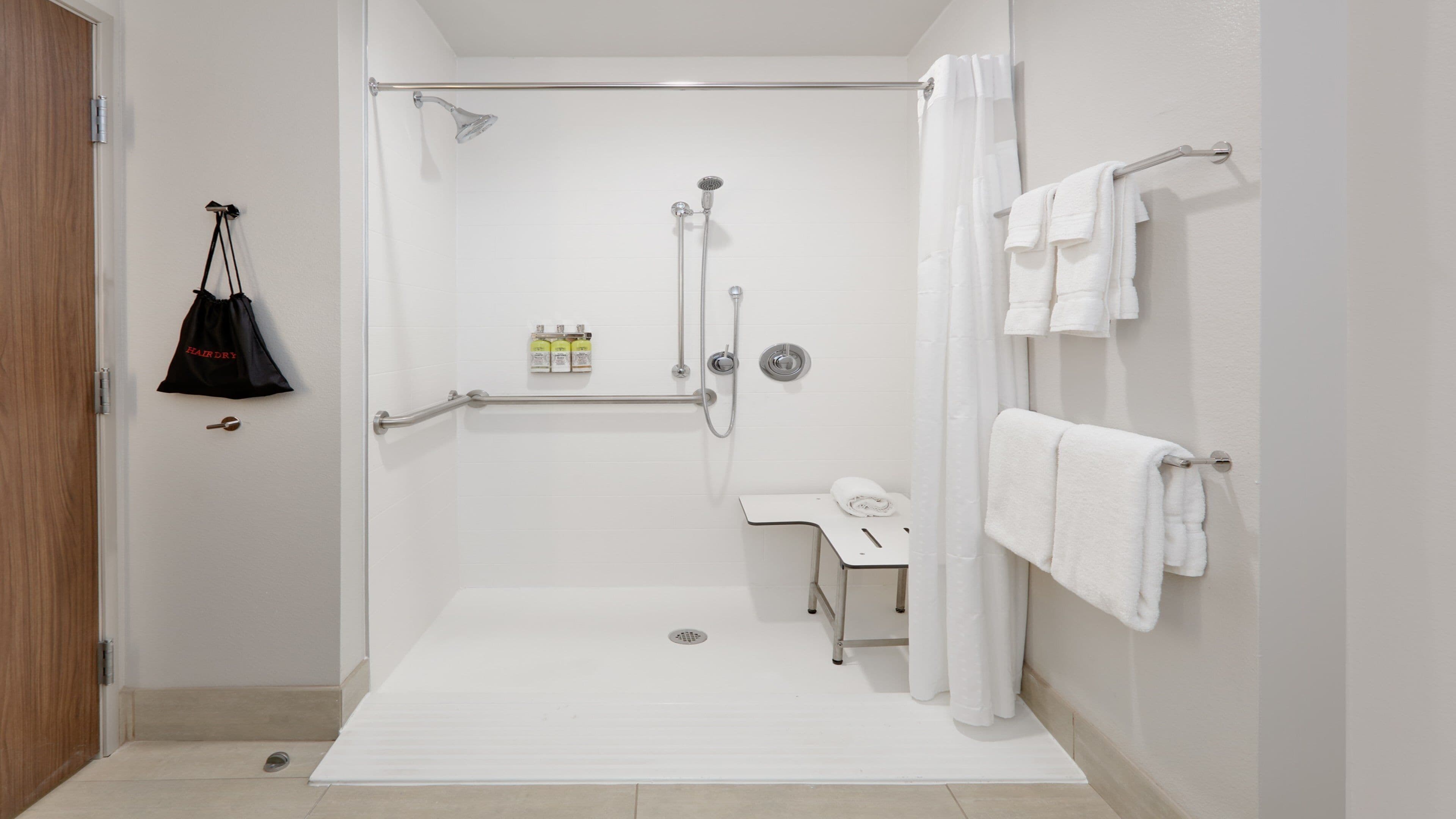 A bathroom with a shower, a toilet, a sink, and a towel rack.