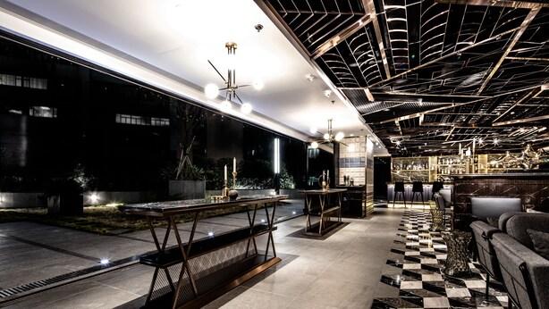 A modern interior with a checkered floor, contemporary furniture, and a ceiling with unique lighting fixtures. - Hotel COZi · Oasis (Kwai Chung)