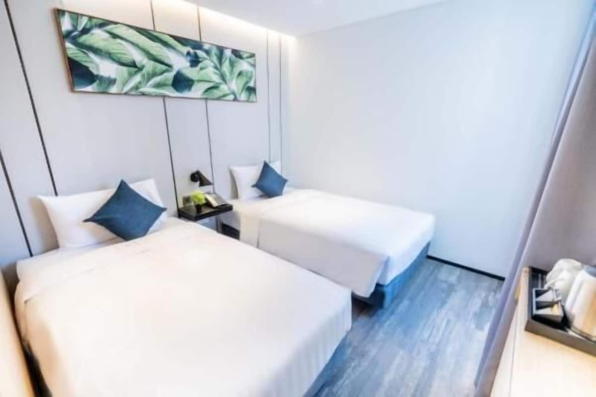 A hotel room with two beds, a nightstand with a lamp, and a painting on the wall.