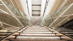 A modern interior with a central staircase flanked by glass railings and illuminated by linear lights. - Hotel COZi · Oasis (Kwai Chung)