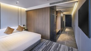 A modern hotel room with a large bed, a bedside table, a TV, and a walk-in closet. - Hotel COZi · Oasis (Kwai Chung)
